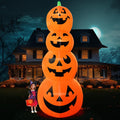 Tall tower of four stacked jack-o'-lantern inflatables beside a child in a witch costume at night