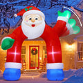 Santa-shaped archway inflatable with a waving mitten over a front walk