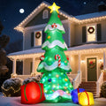 Giant Christmas tree inflatable with a gold star and three gifts in front of a lit house