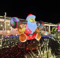 Santa in sunglasses squatting with a peppermint barbell inflatable in a lit yard