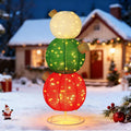 Three stacked glittery lighted ornament balls in white, green and red in a snowy yard