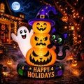 Stacked jack-o'-lanterns in a witch hat with a ghost and a black cat inflatable glowing at night