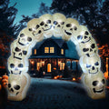 Arch of stacked white skull inflatables glowing over a path to a house at night