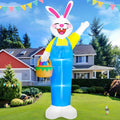 Tall white Easter bunny inflatable in overalls waving and carrying an egg basket in a yard