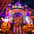 Purple and white haunted castle arch inflatable with a Halloween sign, ghosts and pumpkins at night
